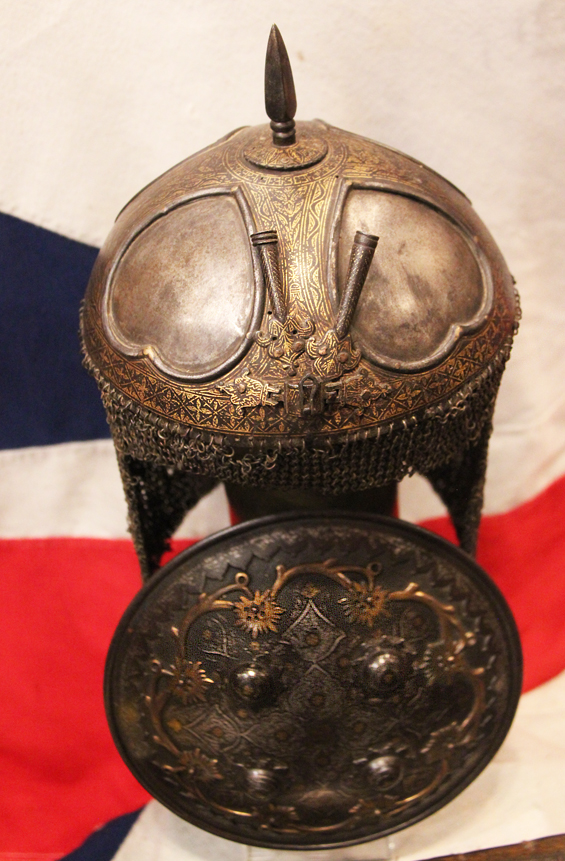 A Gold Inlaid Traditional Persian Armour Suite, of Helmet, Shield & Arm Defence. The Kulah Khud,(کلاهخود) Sipar (سپر), and Bazu Band (بازوبند). Late 18th to Early 19th Century, Possibly Wootz Steel { Pulad}