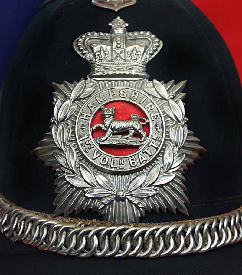 A Superb Victorian Service Helmet of the Hampshire Regiment, the Ist Volunteer Battalion. Blue Cloth with Silver Badge, Fittings, Spike, & Rose Head Curb Chain Mounts and Chin Chain