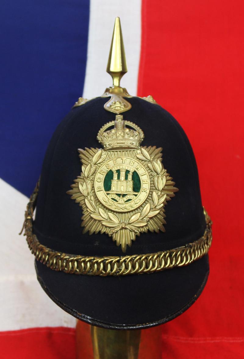 A Superb Antique Edwardian Service Helmet of The Dorsetshire Regiment. Blue Cloth with Gold Badge, Fittings, Spike, & Rose Head Curb Chain Mounts and Chin Chain